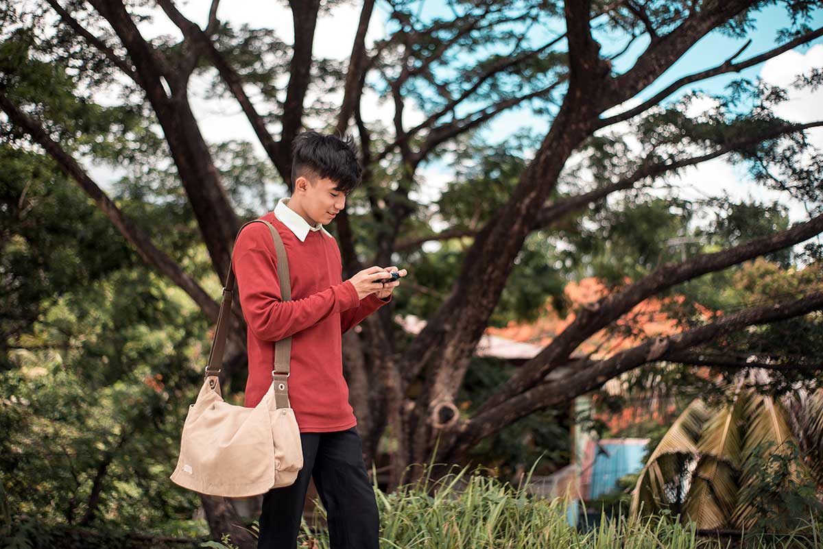 Gen Z age student walks and stares at smartphone