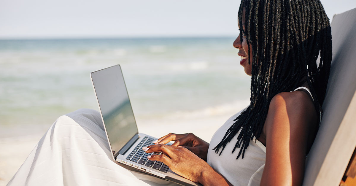 Woman working on laptop in a remote beach location