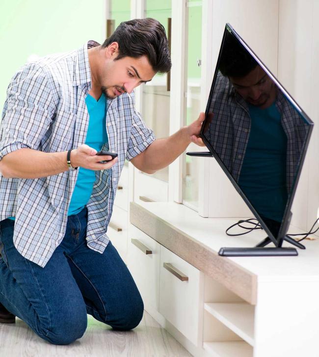 Man on smartphone to repair his television