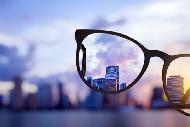 Image of eyeglasses bringing into focus a distant city