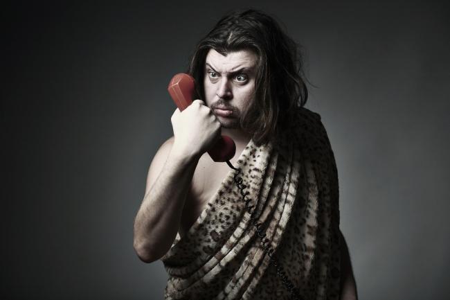 caveman holding a red telephone from the 90s illustrating the history of business process outsourcing