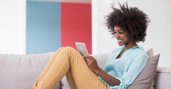 Happy young woman works on tablet at home