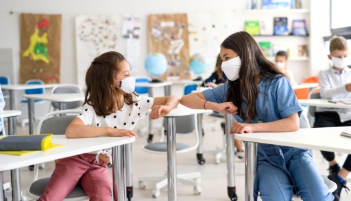 Children with face mask back at school after covid-19 quarantine and lockdown, greeting