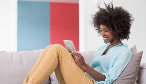 Happy young woman works on tablet at home